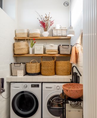 Home laundry in white tones with washing machines and shelves full of clothes baskets