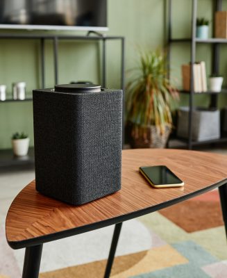 Background image of smart speaker with home AI system on wooden table in modern interior, copy space